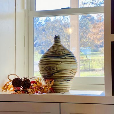 Hand thrown large coil vase in window with autumn leave