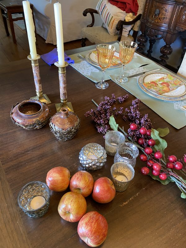 fall tablescape elements purple clusters and red berry faux stems, apples,mercury glass votives, candlesticks,pottery pieces