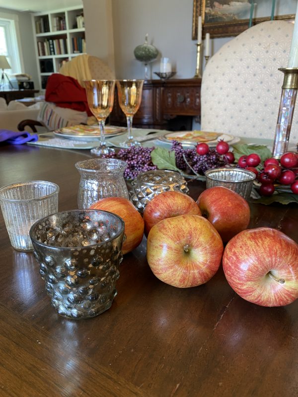 fall tablescape elements purple clusters and red berry faux stems, apples,mercury glass votives, candlesticks,pottery pieces