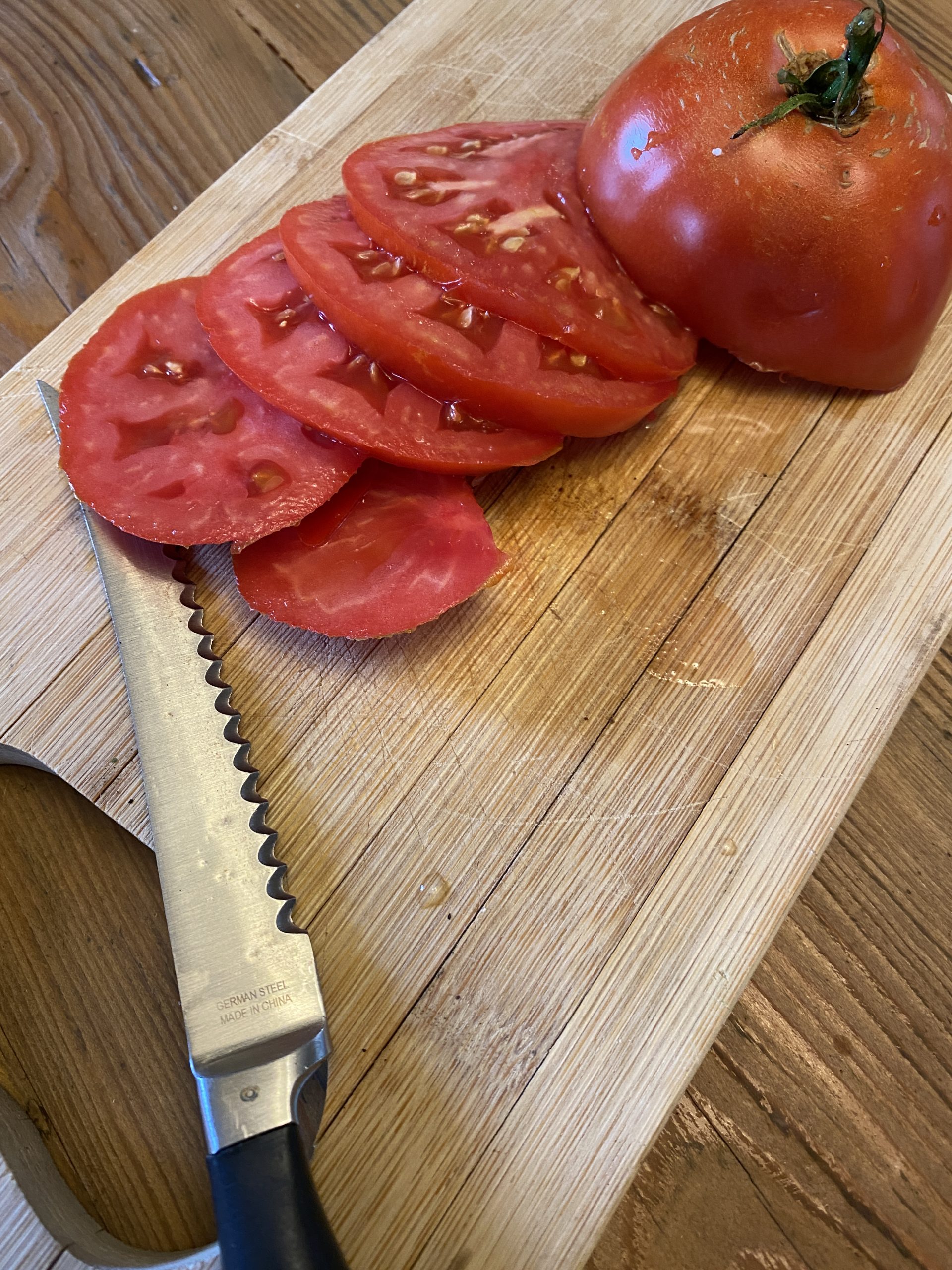 Garden freshly picked tomato sliced with unique tomato slicing knife on mini cutting board