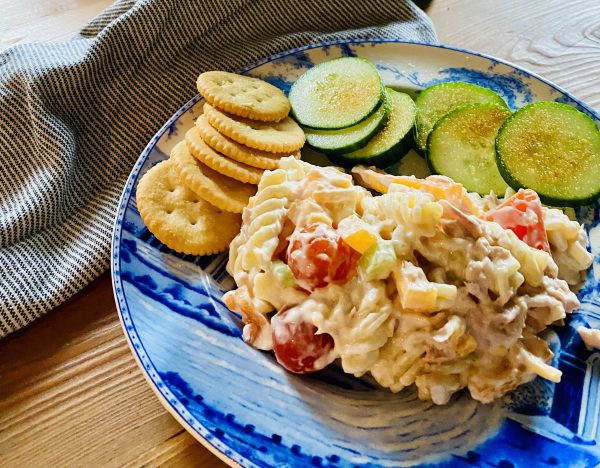 Tuna Pasta Salad is served on blue and white luncheon plate with Ritz crakers adn cucumber slices