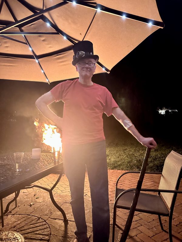 Jim in top hat on patio with fire pit on the background.